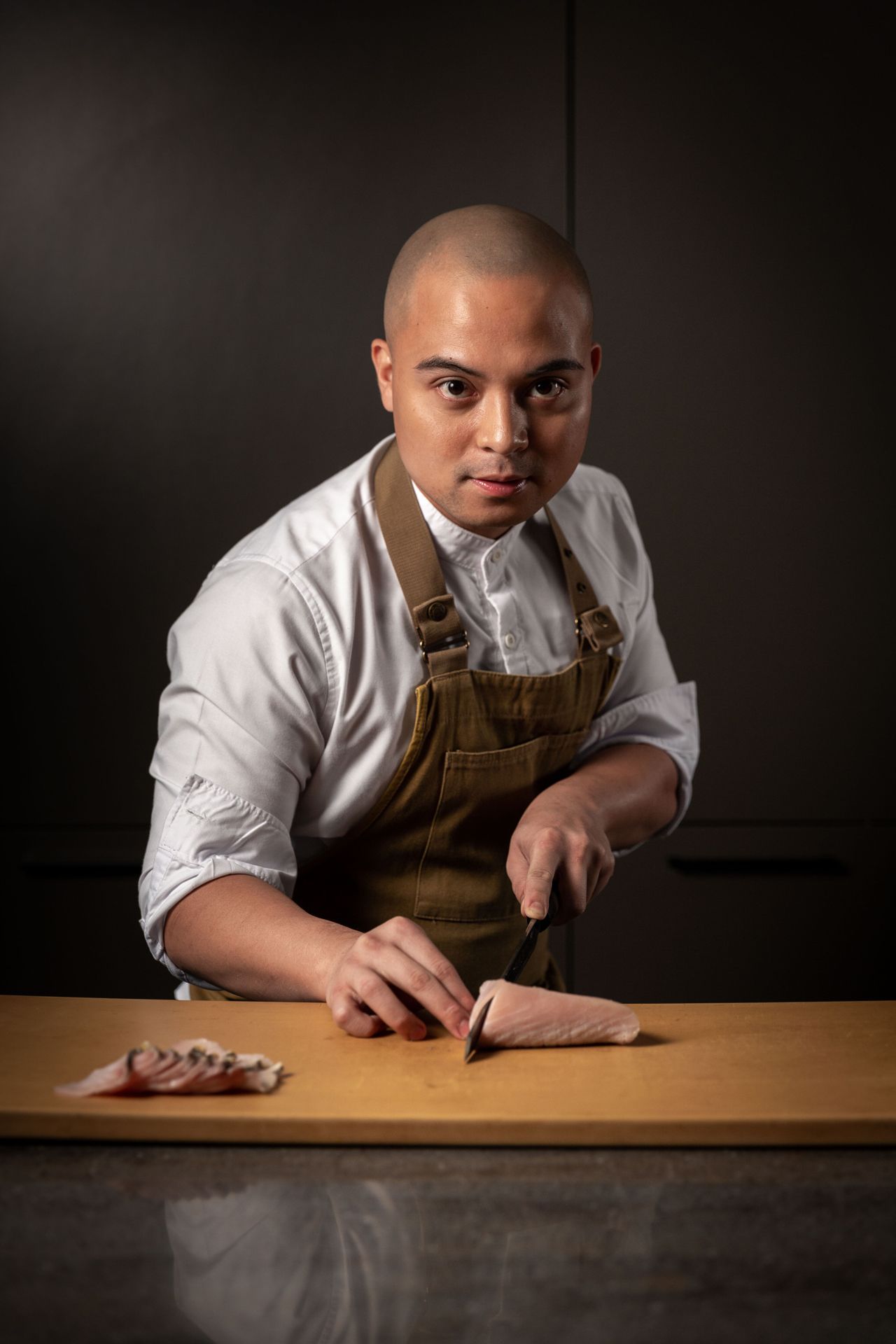 A picture of a filipino chef wielding a knife and posing with a serious face.