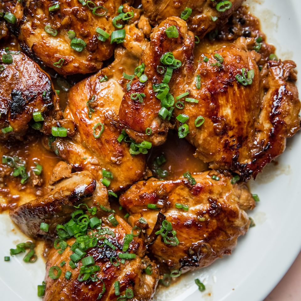 Picture of a completely finished chicken adobo dish served over steam rice on a white plate.