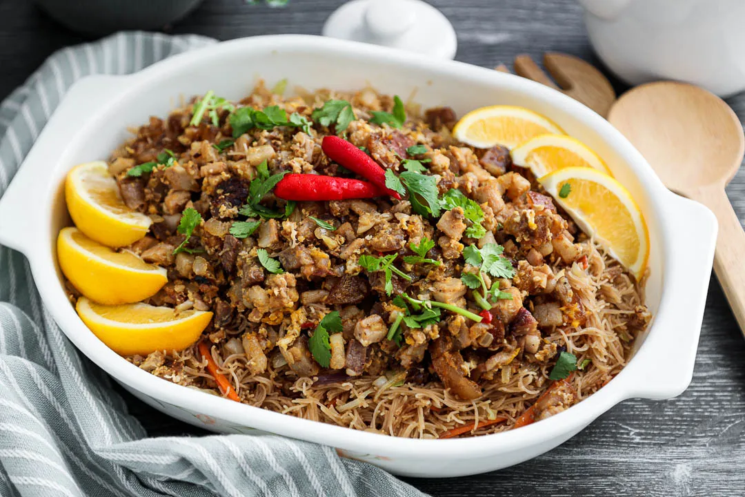 Picture of a completely finished pancit sisig dish with sliced lemons outlining the dish.